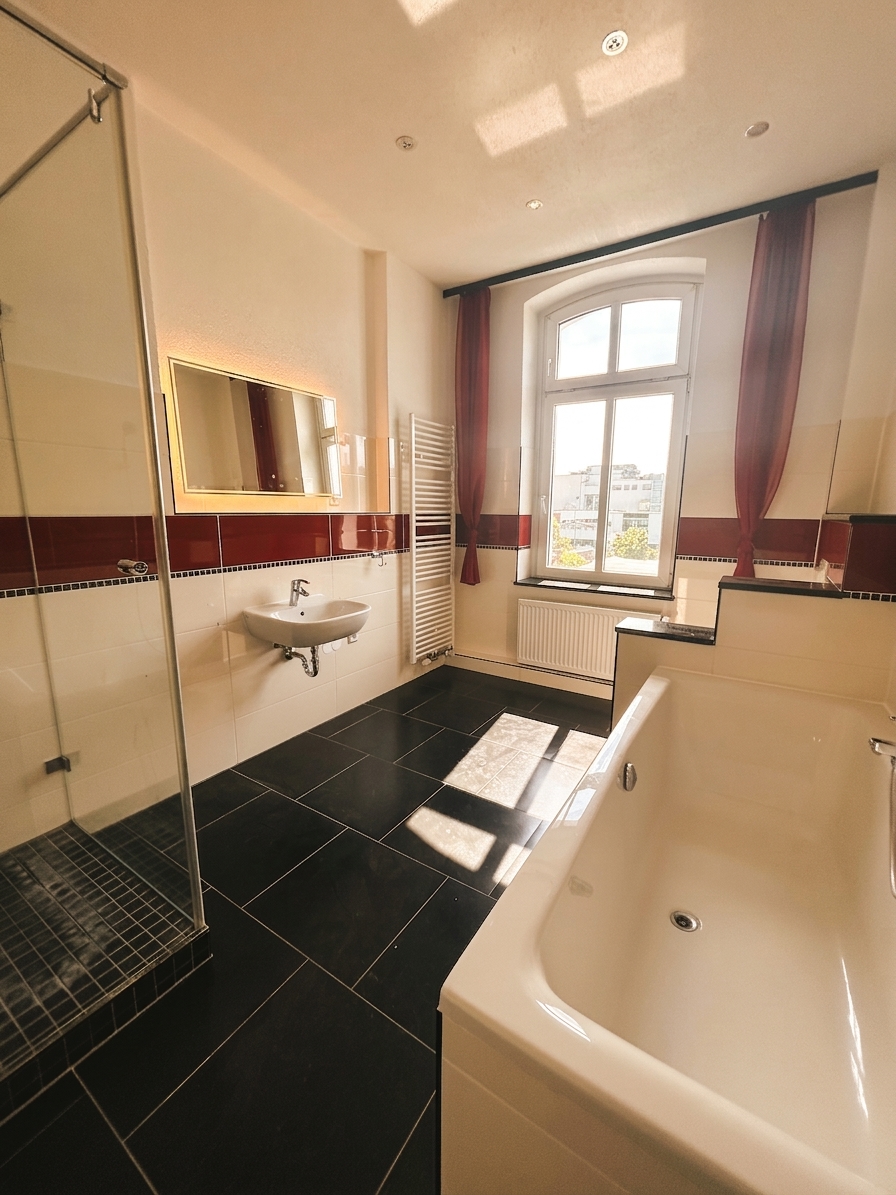 Großzügiges Altbau-Badezimmer mit freistehender Badewanne, Glasdusche, dunklem Fliesenboden und Bogenfenster – 3-Zimmer-Wohnung in Dessau-Roßlau