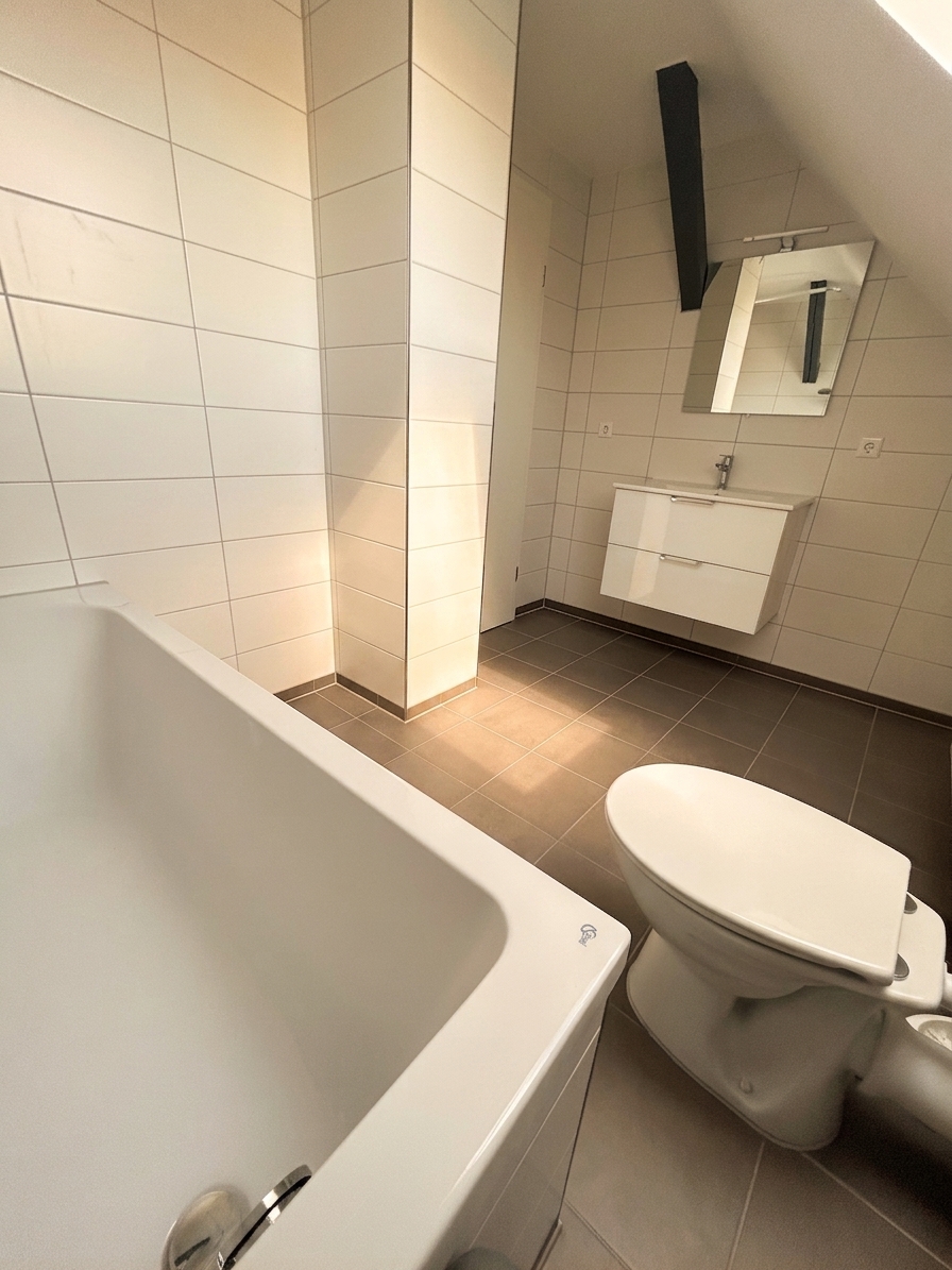 Helles Badezimmer mit Badewanne, WC und Waschtisch unter Dachschräge – Dachgeschosswohnung Dessau
