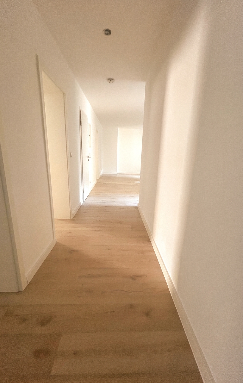 Langer heller Flur mit hellem Holzboden und mehreren Zimmertüren – 4-Zimmer-Wohnung in Dessau-Roßlau