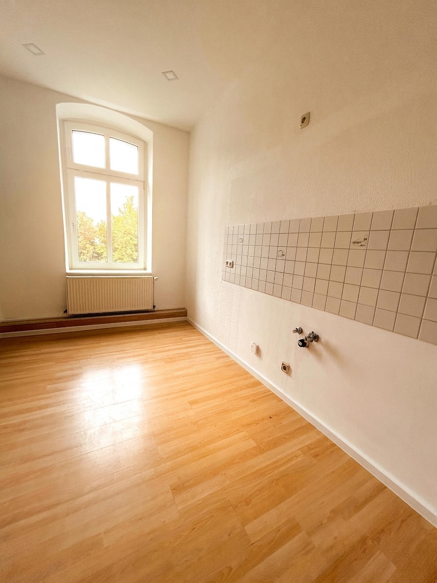 Helle Küche mit warmem Holzboden, Bogenfenster und Fliesenspiegel – 3-Zimmer-Wohnung in Dessau-Roßlau