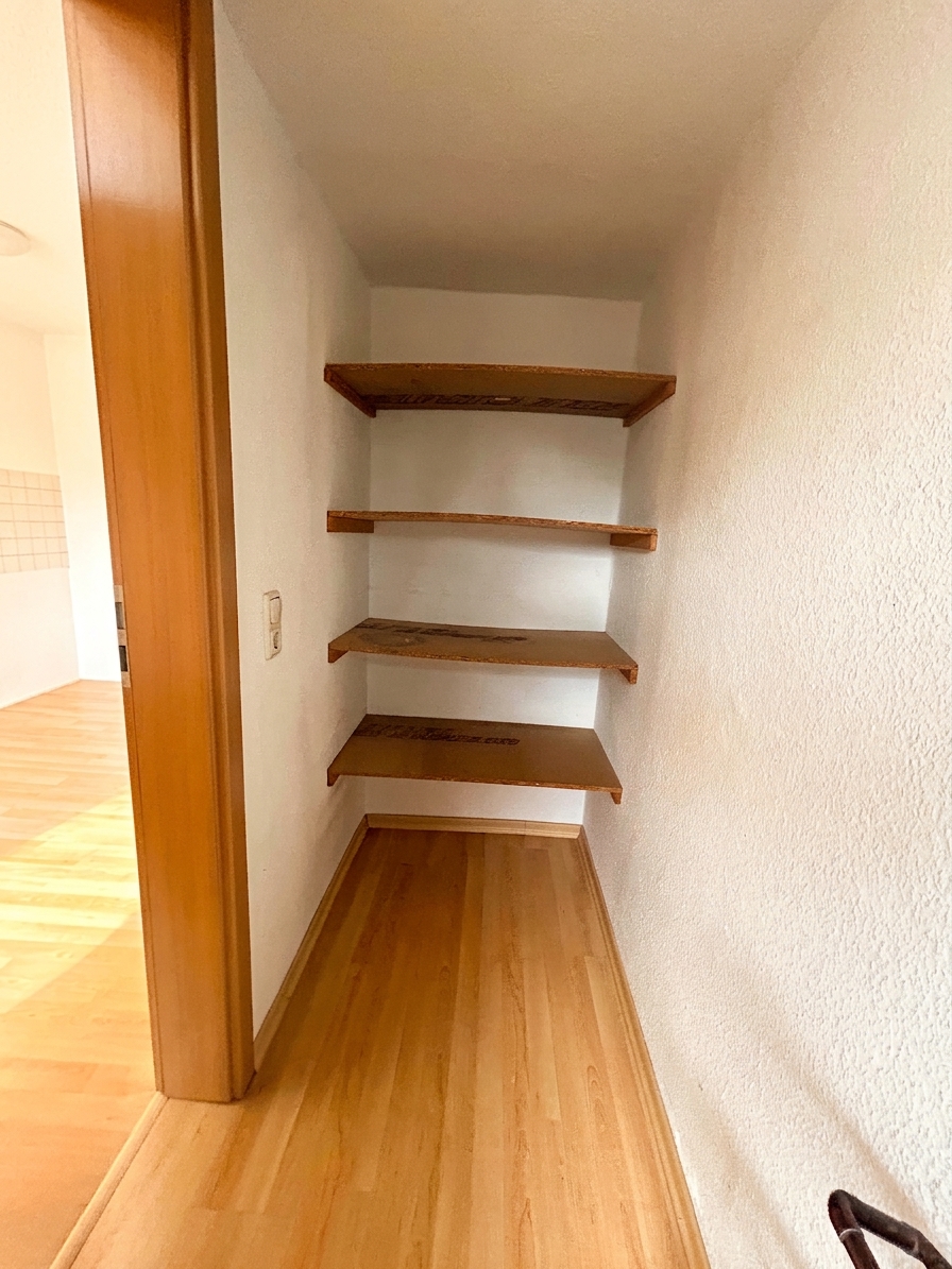 Abstellraum mit eingebauten Holzregalen und warmem Holzboden – 3-Zimmer-Wohnung in Dessau-Roßlau