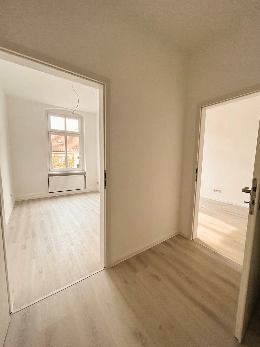 Helles Kinderzimmer mit Durchgang zu weiterem Zimmer mit Bogenfenster und hellem Laminatboden – 4-Zimmer-Wohnung in Dessau-Roßlau