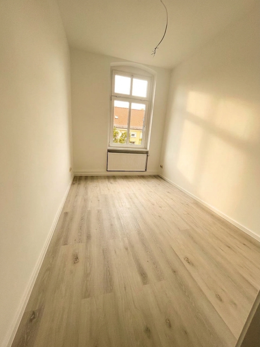 Helles Zimmer mit Bogenfenster, Heizkörper und hellem Laminatboden – 4-Zimmer-Wohnung in Dessau-Roßlau