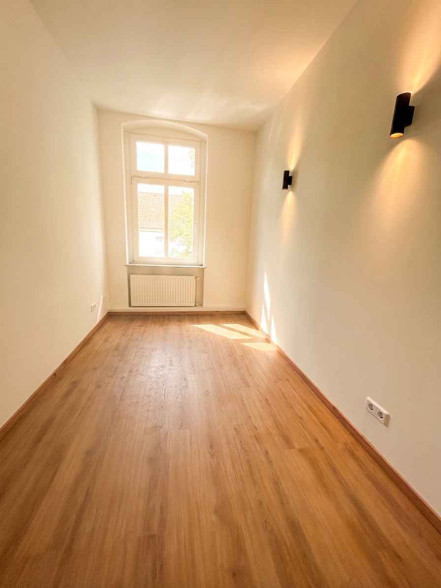 Helles Zimmer mit warmem Holzboden, Bogenfenster und Wandleuchte – 3-Zimmer-Wohnung in Dessau-Roßlau