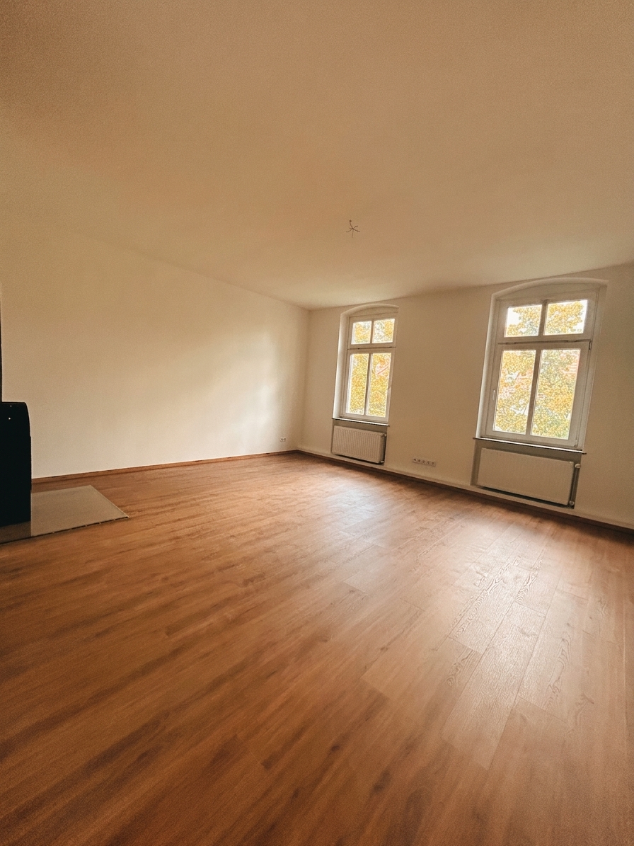 Helles Wohnzimmer mit warmem Holzboden und Bogenfenster – 3-Zimmer-Wohnung in Dessau-Roßlau