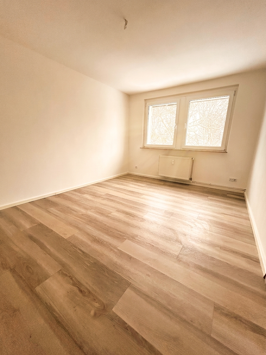 Helles Zimmer mit warmem Laminatboden, weißen Wänden und Doppelfenster – 3-Zimmer-Wohnung in Schorfheide