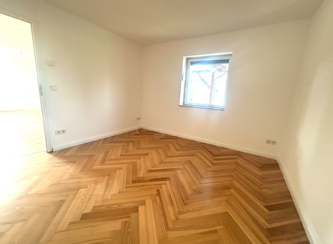 Helles Zimmer mit Fischgrät-Parkett, weißen Wänden und Fenster – 3-Zimmer-Wohnung in Ketzin