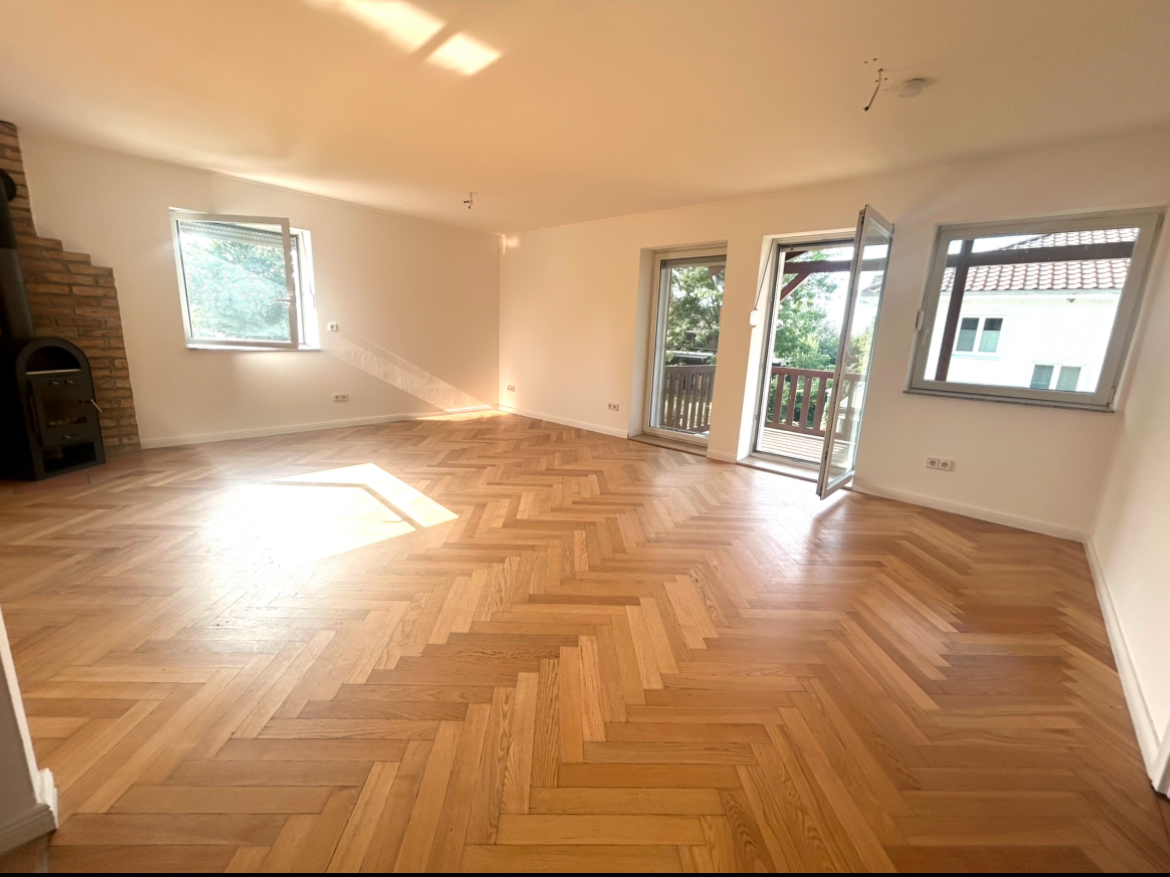 Großes, lichtdurchflutetes Wohnzimmer mit Fischgrät-Parkett, Kamin, Balkonzugang und mehreren Fenstern – 3-Zimmer-Wohnung in Ketzin