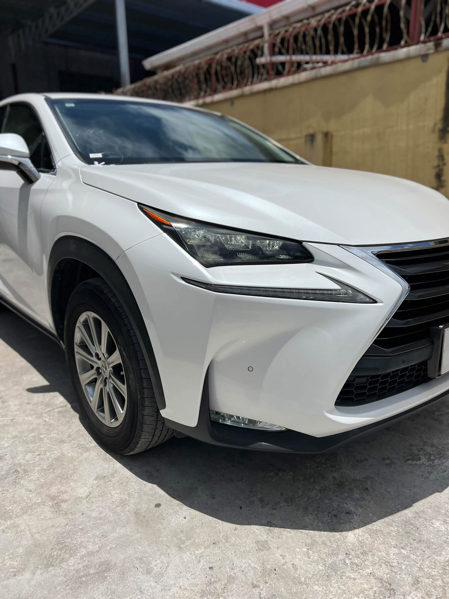 2015 Lexus NX200T Pearl White — three-quarter front angle showing sculpted hood and alloy wheels