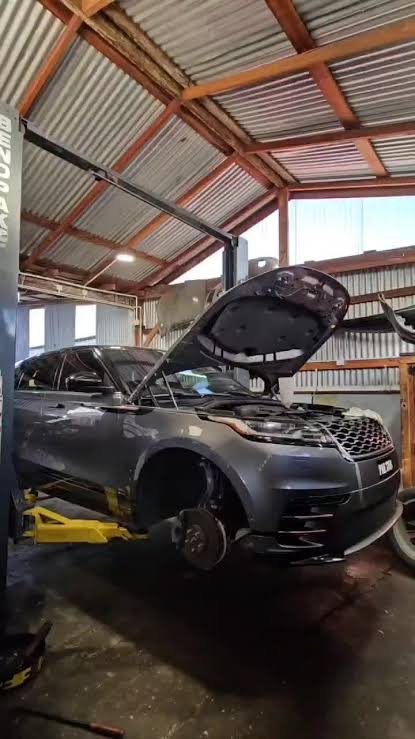 Grey Range Rover Velar with bonnet open on a hydraulic lift inside L.Singh Mechanic Shop workshop