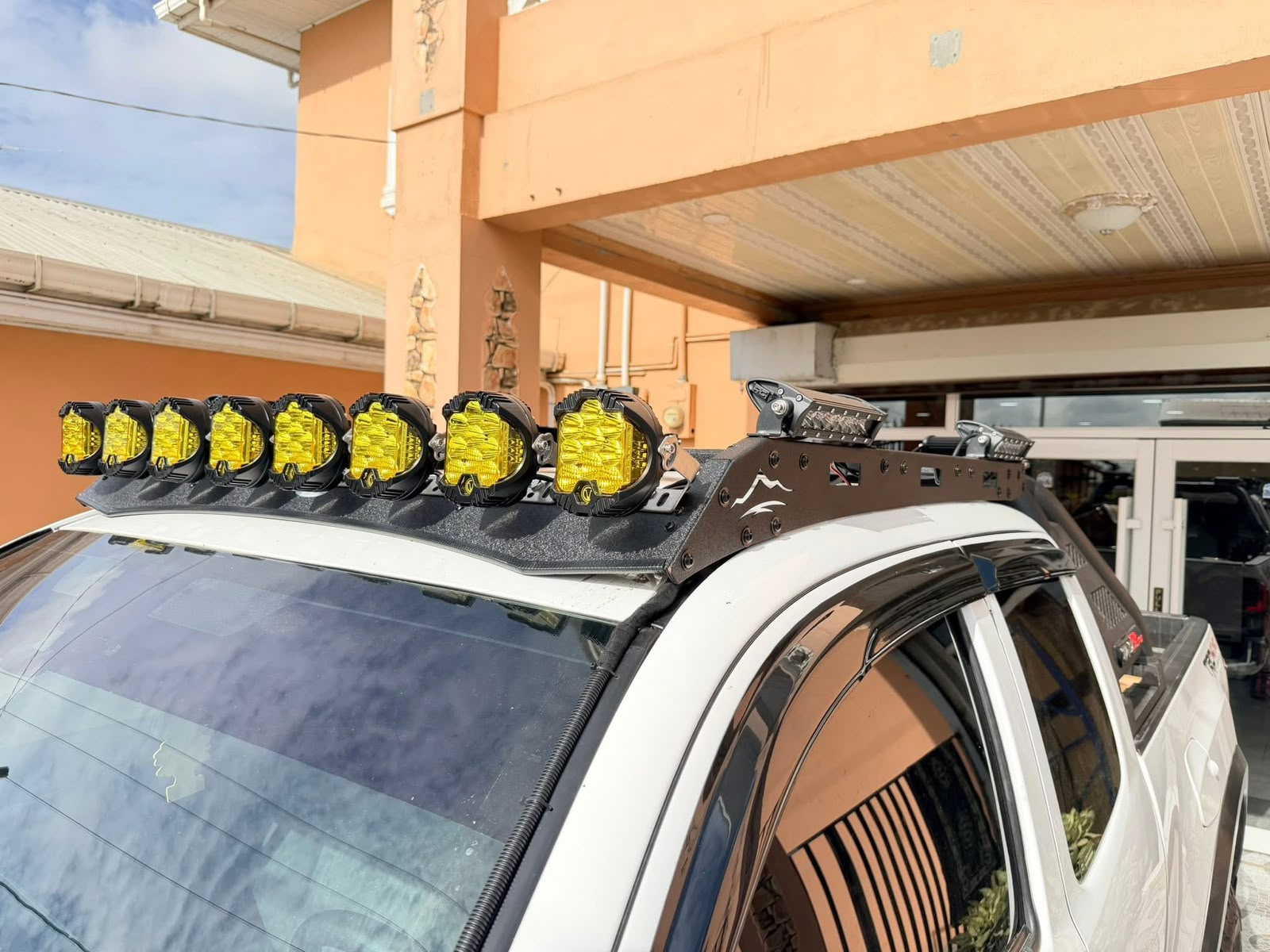 White pickup truck fitted with a custom roof-mounted light bar holding eight yellow LED driving lights, installed at L.Singh Mechanic Shop