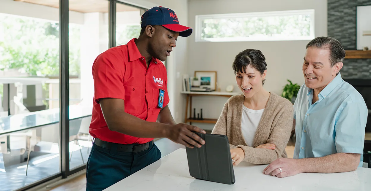 Mr. Rooter technician demonstrating service to homeowners