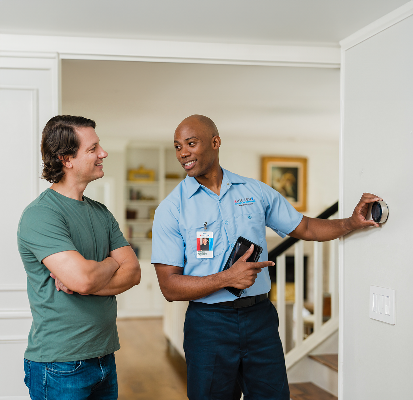 Aire Serv technician explaining thermostat settings to a homeowner
