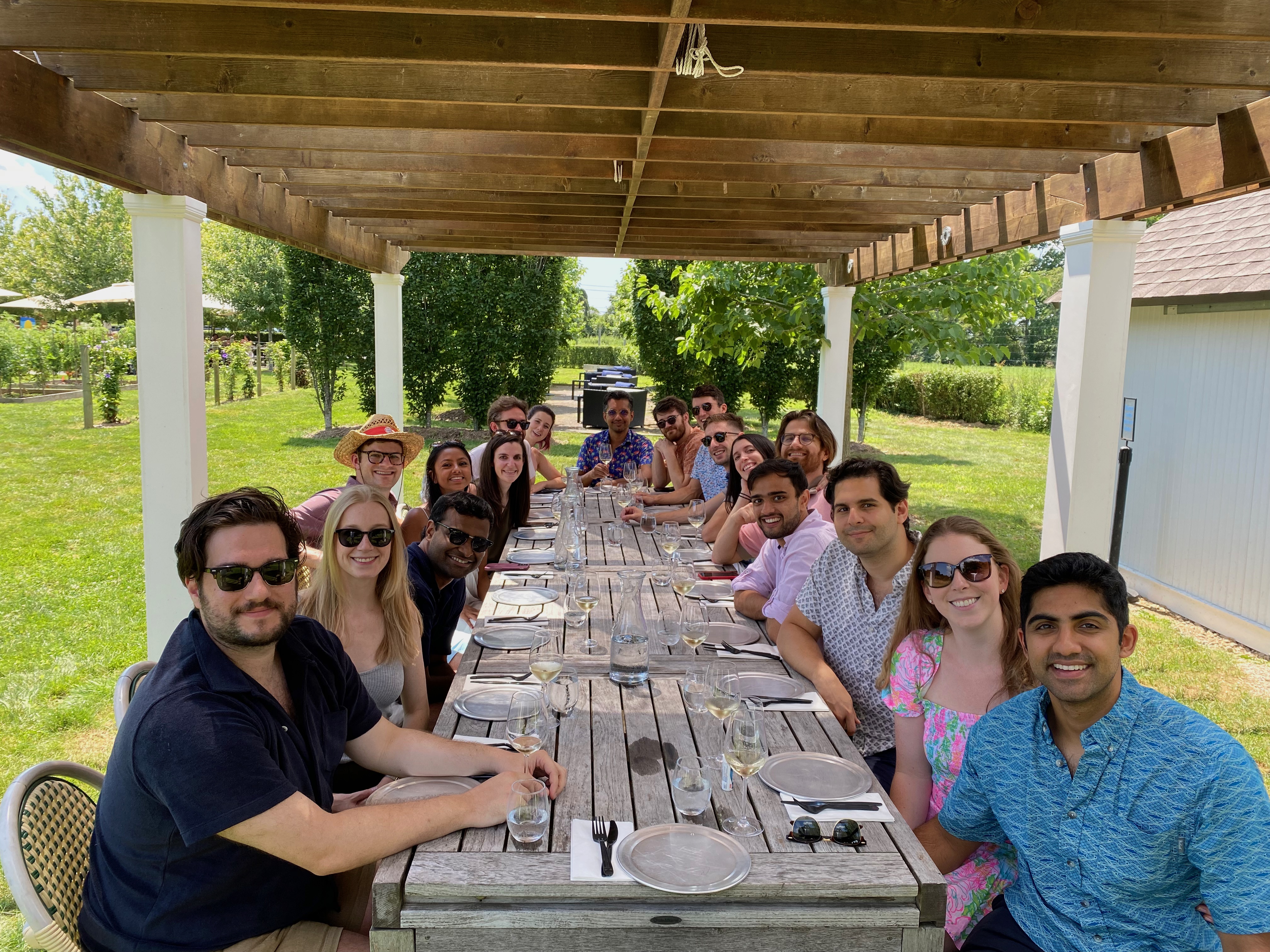 Group dining under a pergola at a vineyard