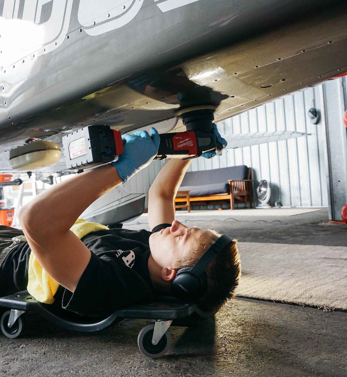 Aircraft cleaning technician polishing the underside of a private aircraft