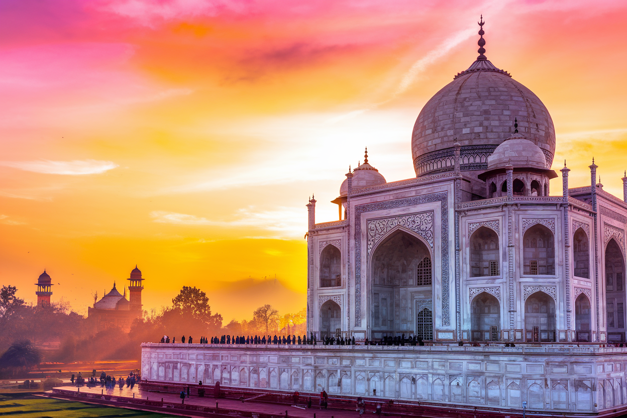 The Taj Mahal glowing in warm sunrise light with visitors walking along the reflecting pool pathway