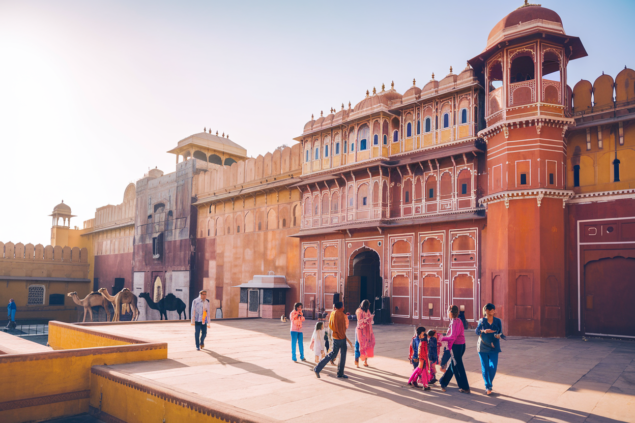 The grand Amber Fort in Jaipur bathed in warm sunlight with visitors exploring its ornate courtyards