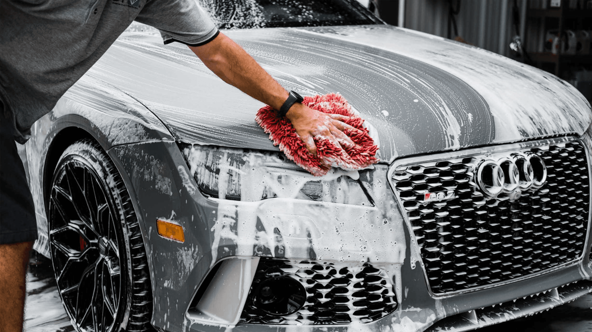 Close-up of car wash with red microfiber mitt on Audi hood