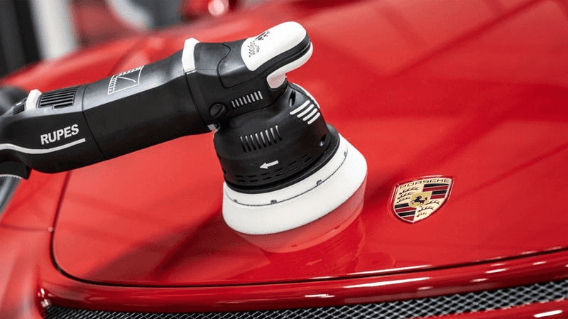 Rupes polisher tool on red Porsche hood